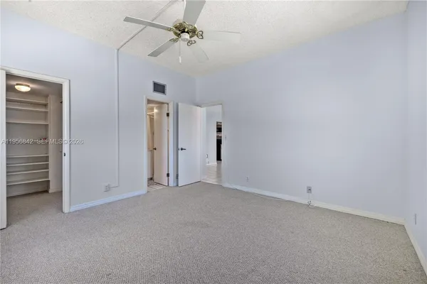 an empty room with a ceiling fan and closet area