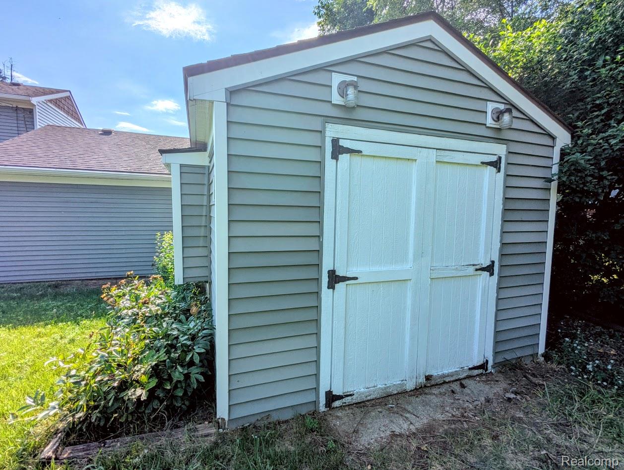 2316 Crescent Lake Road Waterford, MI 48329 - Photo 15 of 17 Exterior storage shed featuring horizontal siding, a gable roof, and white double doors with black hardware