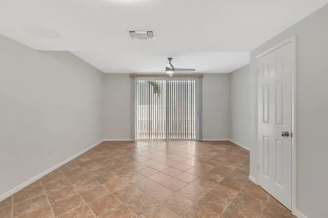 an empty room with chandelier fan and windows