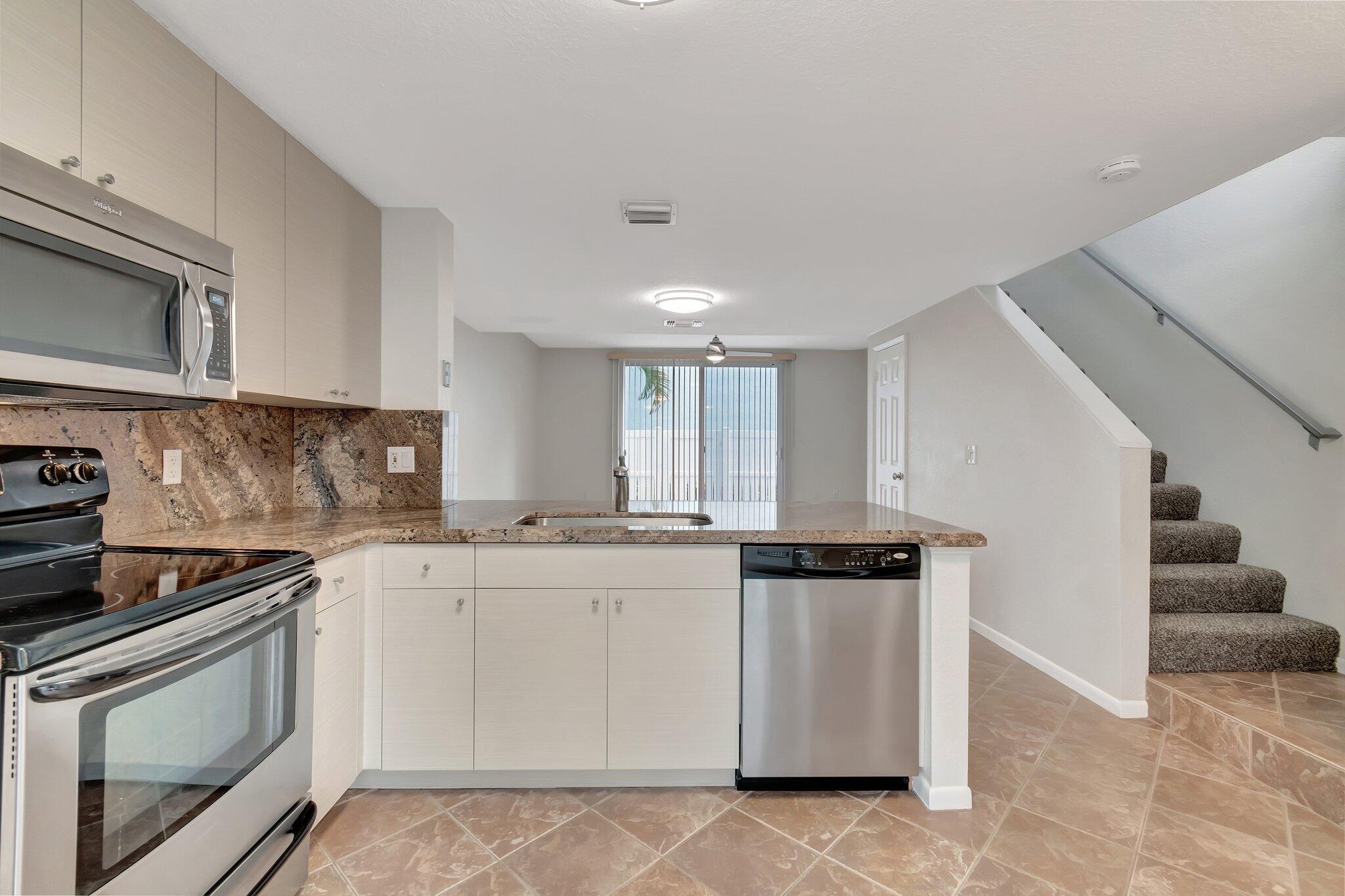 1016 Jeffery Street, Unit 1016 Boca Raton, FL 33487 - Photo 20 of 65 a kitchen with stainless steel appliances granite countertop a stove a sink and a microwave