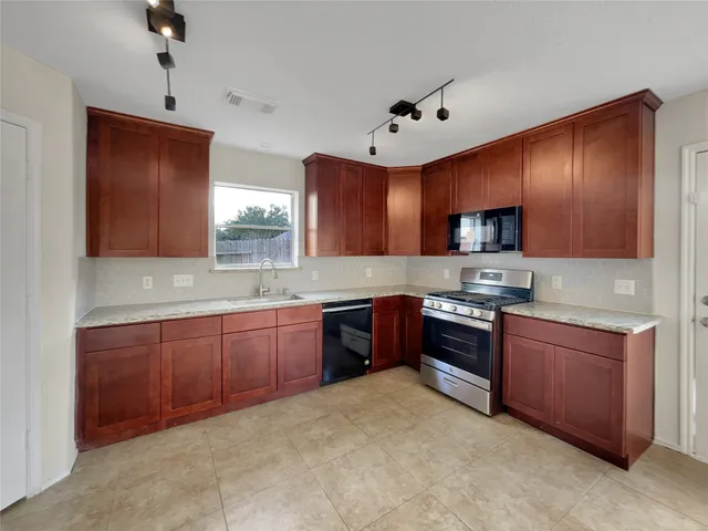 a large kitchen with stainless steel appliances granite countertop a stove sink and cabinets