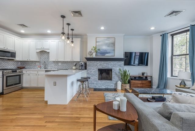 a kitchen with a stove kitchen island and couches with wooden floor