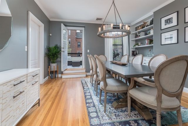 a dining room with wooden floor a chandelier a wooden table and chairs
