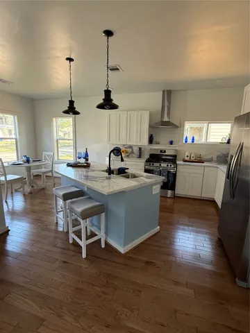 a kitchen with stainless steel appliances granite countertop a sink a stove and wooden floors