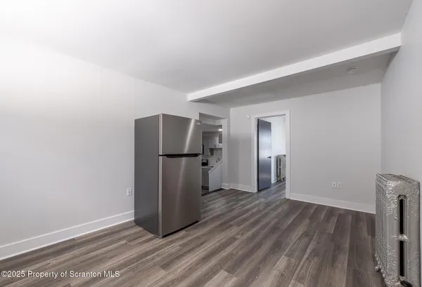 a view of a room with wooden floor and a refrigerator