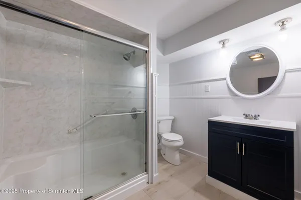 a bathroom with a toilet sink vanity granite and shower