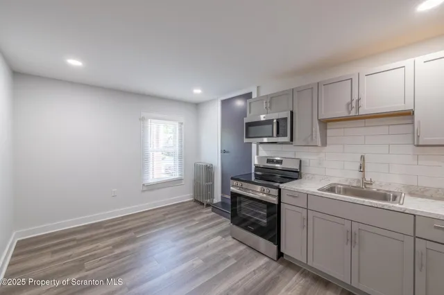 a kitchen with granite countertop white cabinets stainless steel appliances a sink and a window
