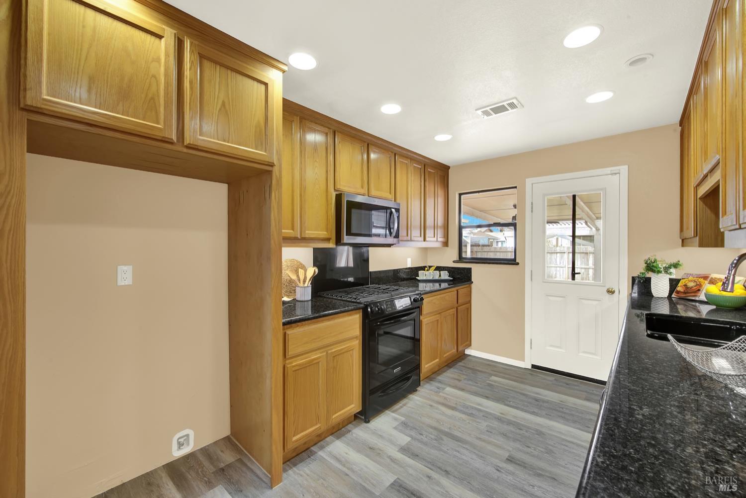 112 East Kentucky Street Fairfield, CA 94533 - Photo 24 of 70 a kitchen with stainless steel appliances granite countertop a refrigerator a stove top oven a sink and dishwasher with wooden floor