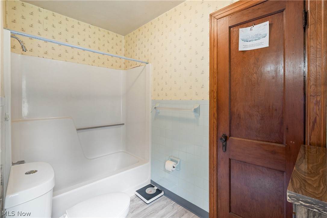 6324 Struthers Road Youngstown, OH 44514 - Photo 29 of 42 Bathroom featuring a white tub-shower combination unit, light blue wall tiling, and a natural wood-finish door