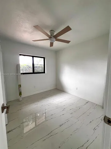 en empty room with windows and ceiling fan
