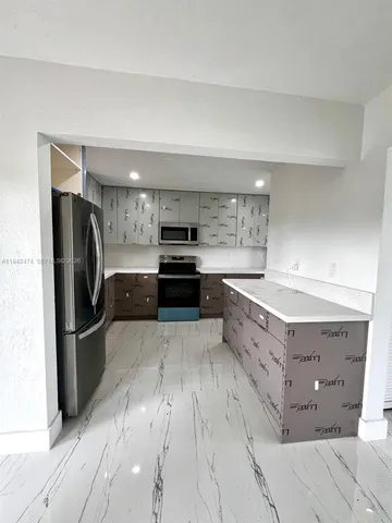 a kitchen with stainless steel appliances granite countertop a refrigerator a stove and a sink