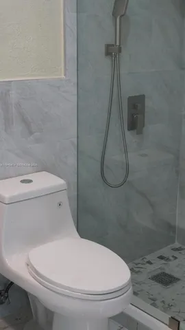 a white toilet sitting next to a bath tub and a shower