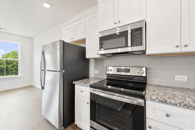 a kitchen with stainless steel appliances white cabinets and a stove a refrigerator with wooden floor