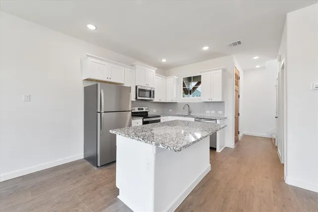 a kitchen with stainless steel appliances granite countertop a refrigerator a sink dishwasher a stove and a refrigerator with wooden floor