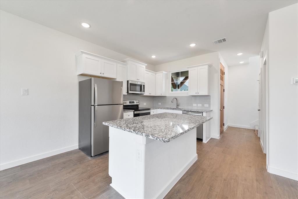 1210 Chestnut Court, Unit 1 Runaway Bay, TX 76426 - Photo 7 of 29 a kitchen with stainless steel appliances granite countertop a refrigerator a sink dishwasher a stove and a refrigerator with wooden floor