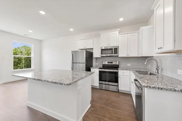 a kitchen with kitchen island granite countertop a stove sink and microwave