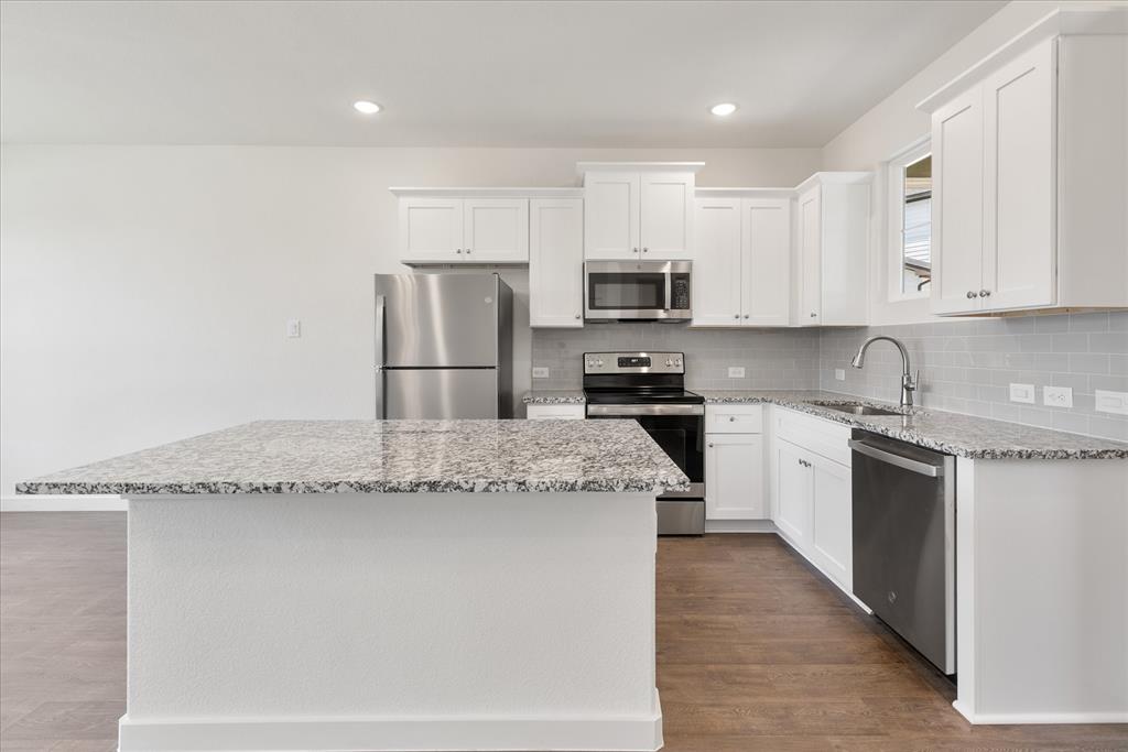 1210 Chestnut Court, Unit 1 Runaway Bay, TX 76426 - Photo 9 of 29 a kitchen with granite countertop a sink stainless steel appliances and white cabinets