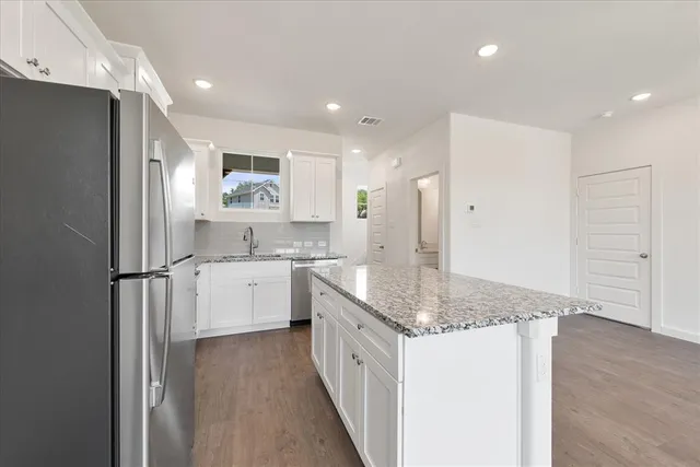 a large kitchen with granite countertop a sink and refrigerator