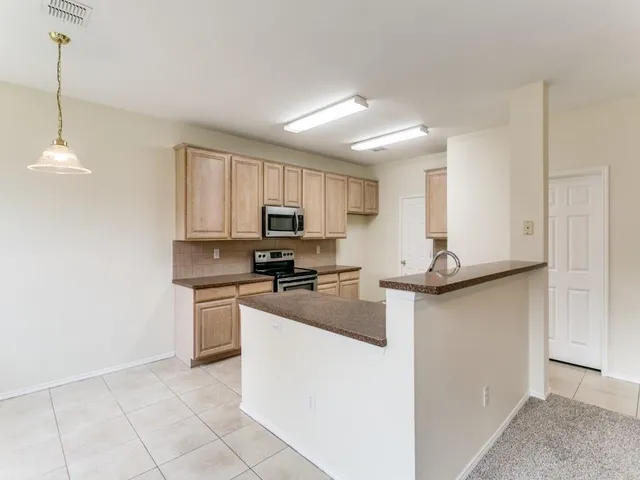 a kitchen with kitchen island granite countertop stainless steel appliances a sink a stove a microwave a center island and cabinets