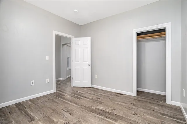 a view of an empty room with wooden floor and closet