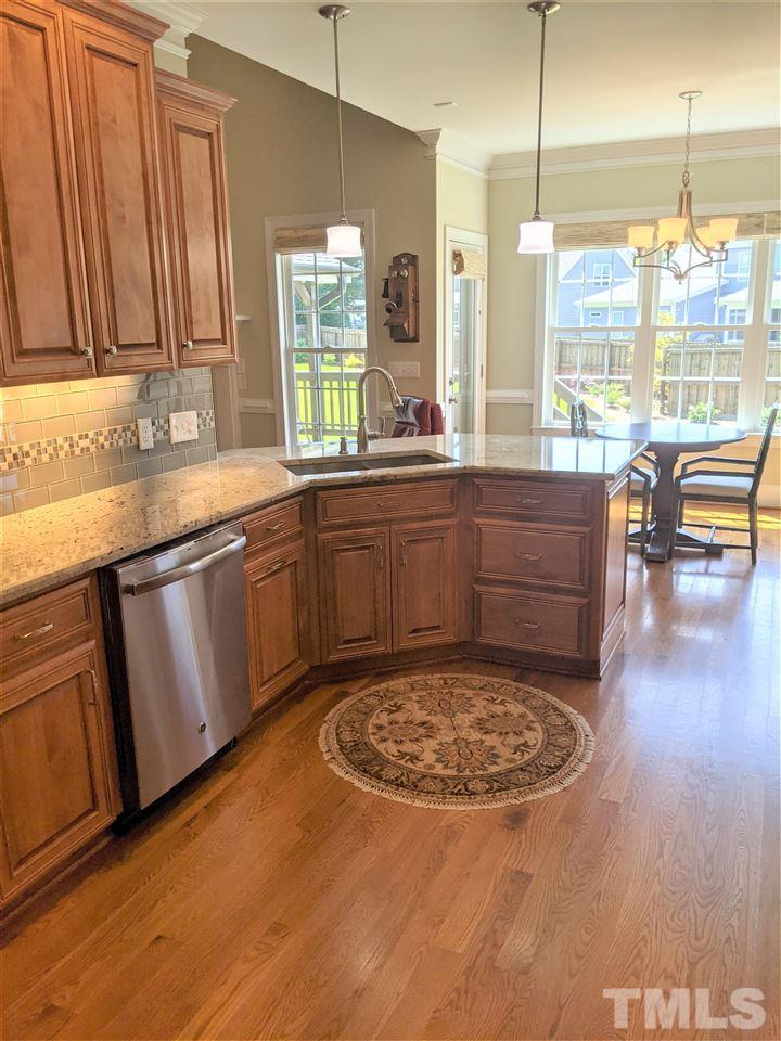 2729 Howard Road Raleigh, NC 27613 - Photo 8 of 26 a large kitchen with kitchen island granite countertop a sink window and white cabinets