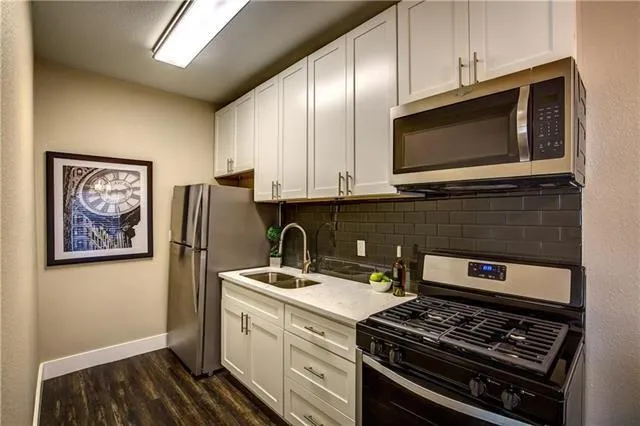 a kitchen with stainless steel appliances a stove a microwave and a sink