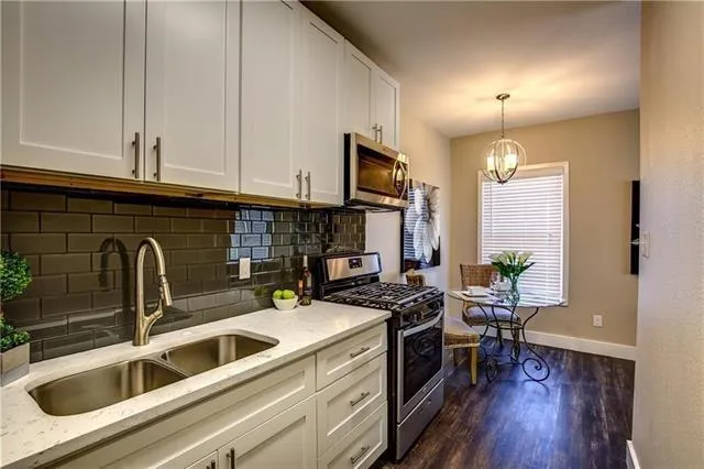 a kitchen with stainless steel appliances a sink a stove top oven a counter space and cabinets
