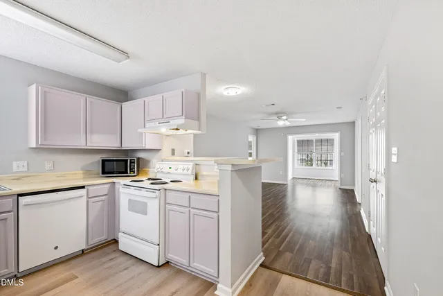 a kitchen with a sink a stove cabinets and wooden floor