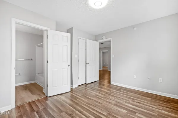 a view of an empty room with wooden floor and closet