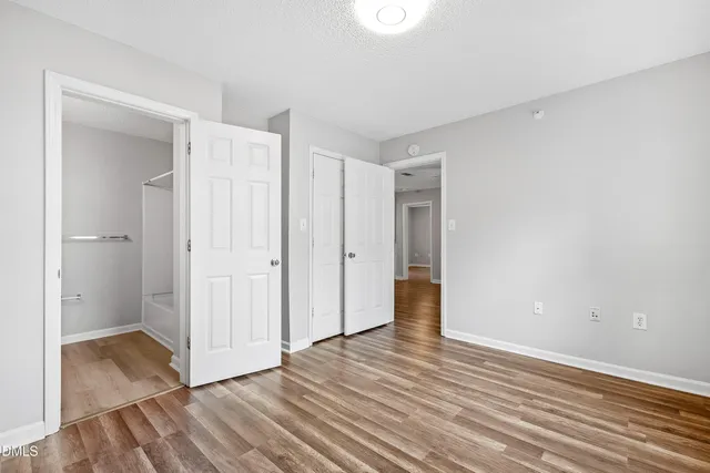 a view of an empty room with wooden floor and closet