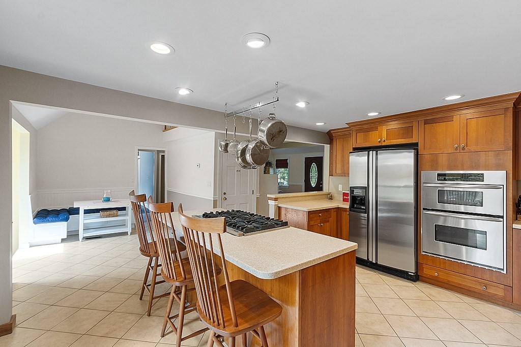 113 Green Road Bolton, MA 01740 - Photo 7 of 41 a kitchen with stainless steel appliances kitchen island granite countertop a table chairs and a refrigerator