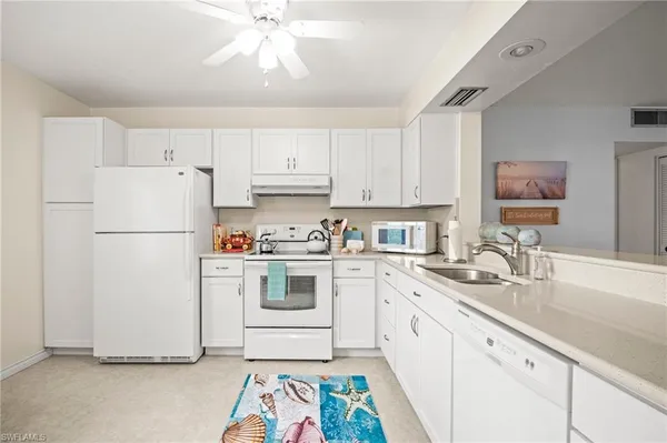 a kitchen with a sink a refrigerator and white cabinets