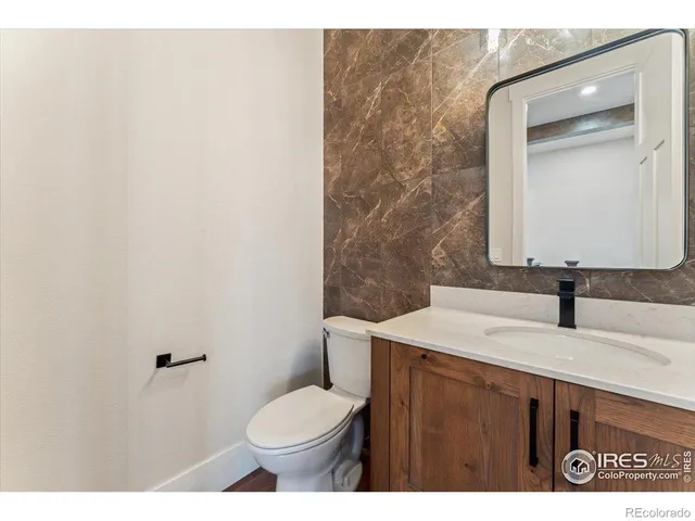 a bathroom with a granite countertop sink vanity mirror and toilet