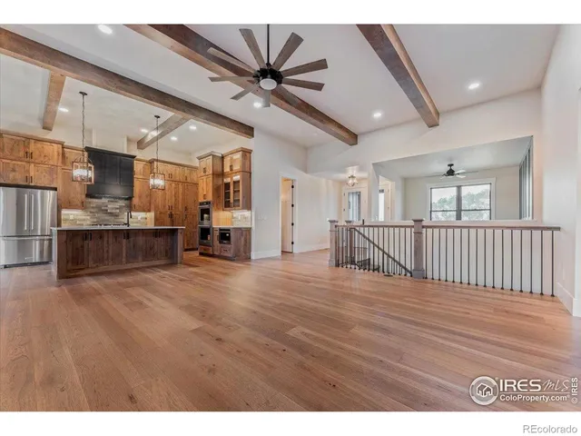 a view of empty room with wooden floor and fan