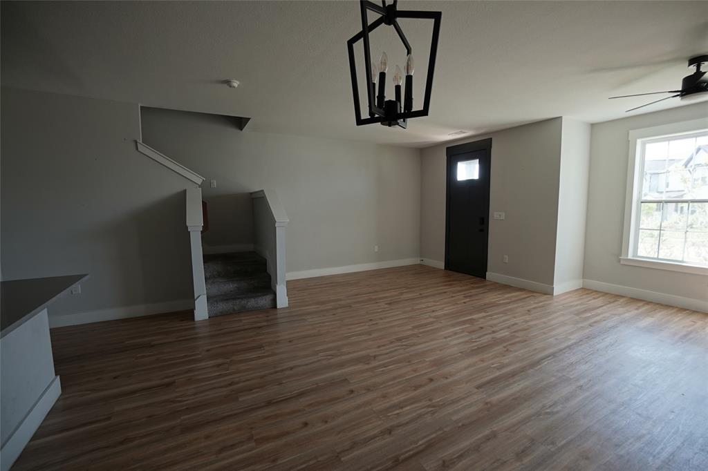 1764 Palladio Loop Princeton, TX 75407 - Photo 11 of 40 Spacious open-concept room featuring wood-finish flooring, a contemporary black ceiling fan, and a modern black chandelier