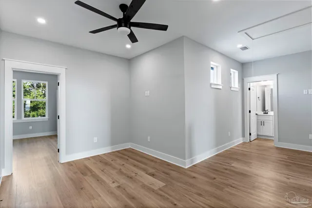 a view of empty room with wooden floor and fan