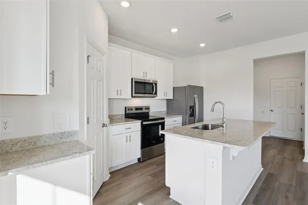 a kitchen with a sink a stove a refrigerator a oven and white cabinets