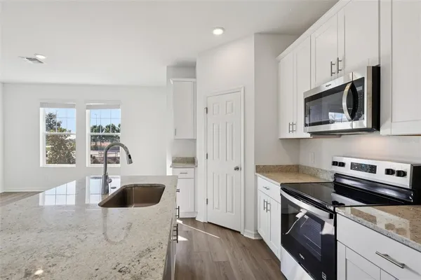 a kitchen with stainless steel appliances granite countertop a sink a stove a microwave and cabinets