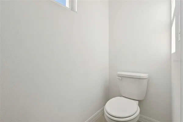 a white toilet sitting next to a white wall
