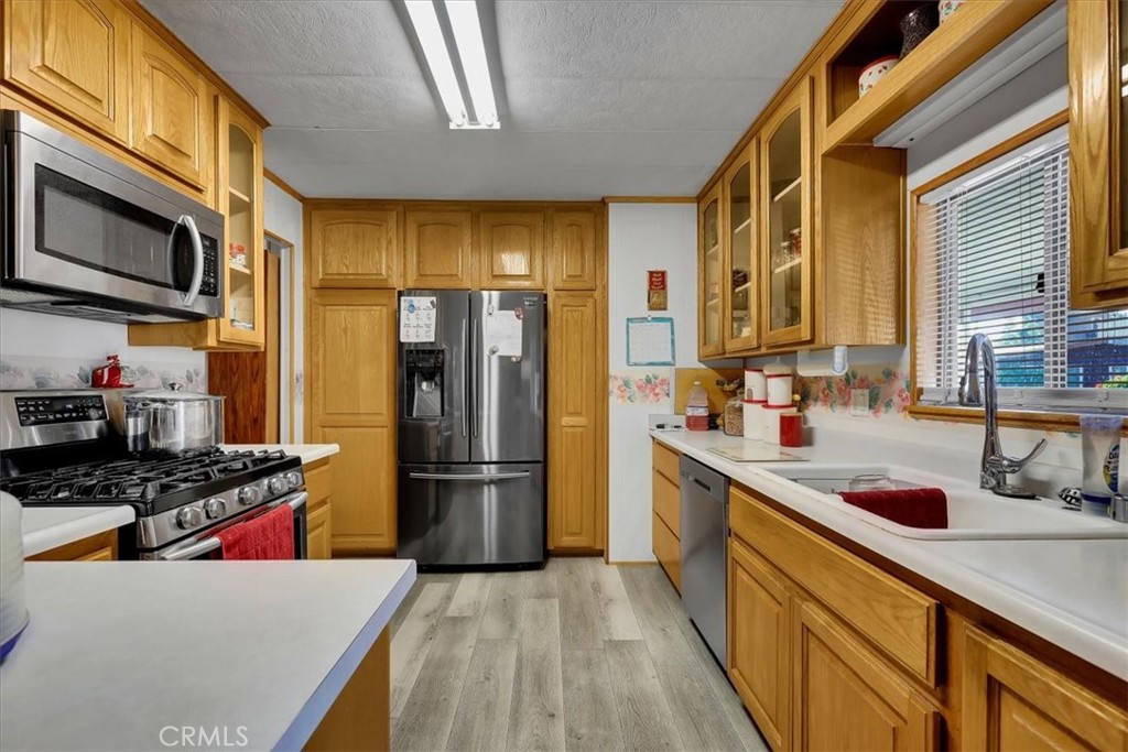 9800 Base Line Road, Unit 114 Rancho Cucamonga, CA 91701 - Photo 15 of 48 a kitchen with stainless steel appliances a refrigerator a sink and wooden cabinets