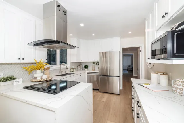 a kitchen with stainless steel appliances a dining table chairs and a refrigerator