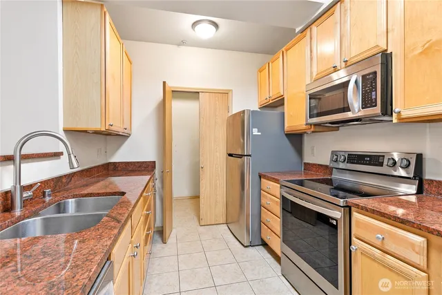 a kitchen with granite countertop a refrigerator and a stove top oven