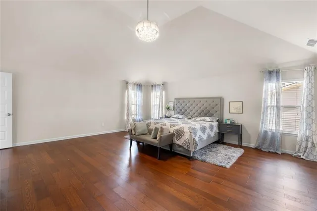 a spacious bedroom with a bed and wooden floor