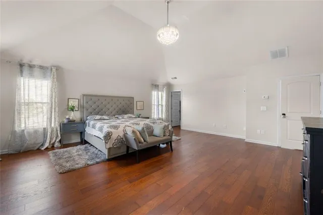 a bed sitting in a spacious bedroom next to a window and a chandelier