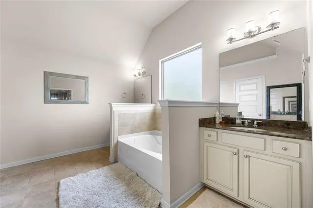 a en suite bathroom with a granite countertop sink and a mirror