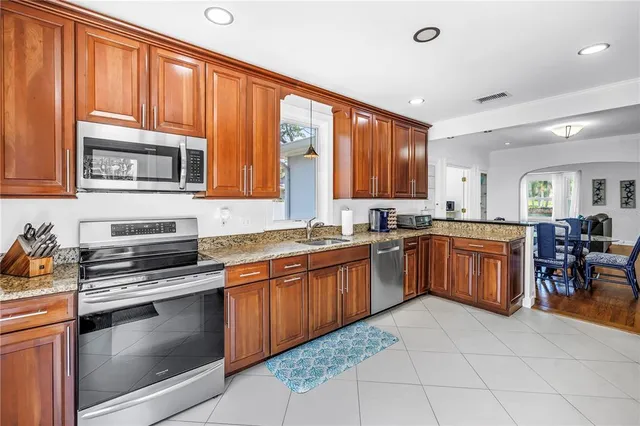 a kitchen with stainless steel appliances granite countertop wooden cabinets a stove top oven a sink and dishwasher