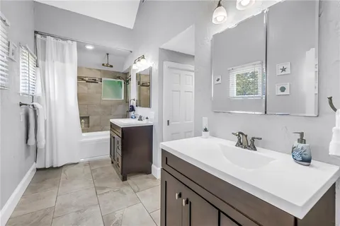 a bathroom with a sink vanity granite tub shower and a mirror