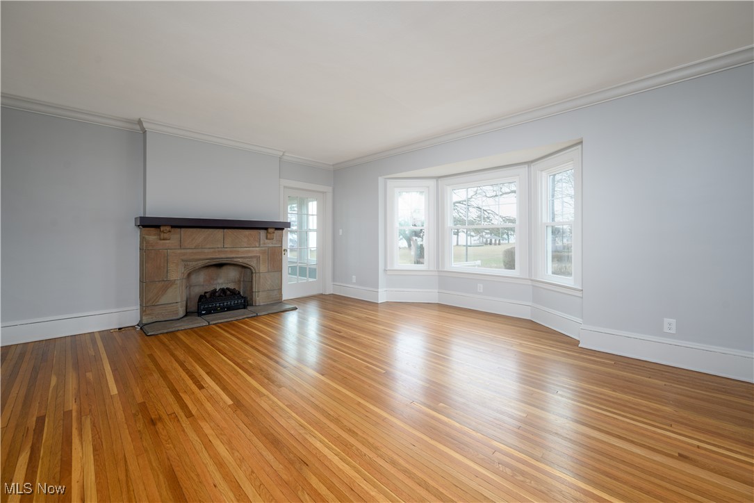 17728 Windward Road Cleveland, OH 44119 - Photo 11 of 32 Unfurnished living room with crown molding, a tile fireplace, and light wood-type flooring