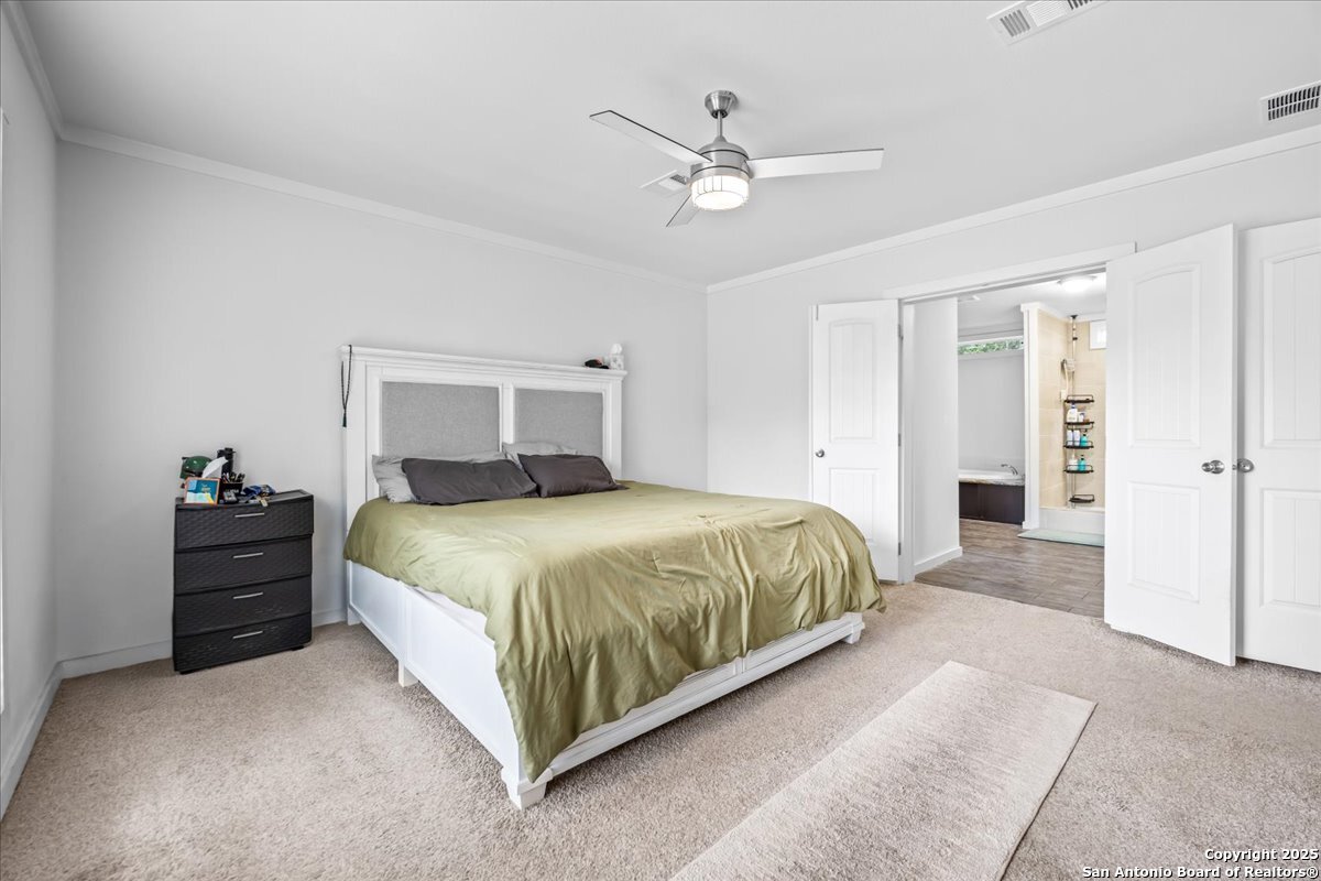 1291 Vivroux Ranch Road Seguin, TX 78155 - Photo 14 of 44 a bedroom with a large bed and a chandelier