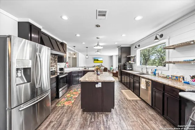 a large kitchen with stainless steel appliances granite countertop a stove and a refrigerator